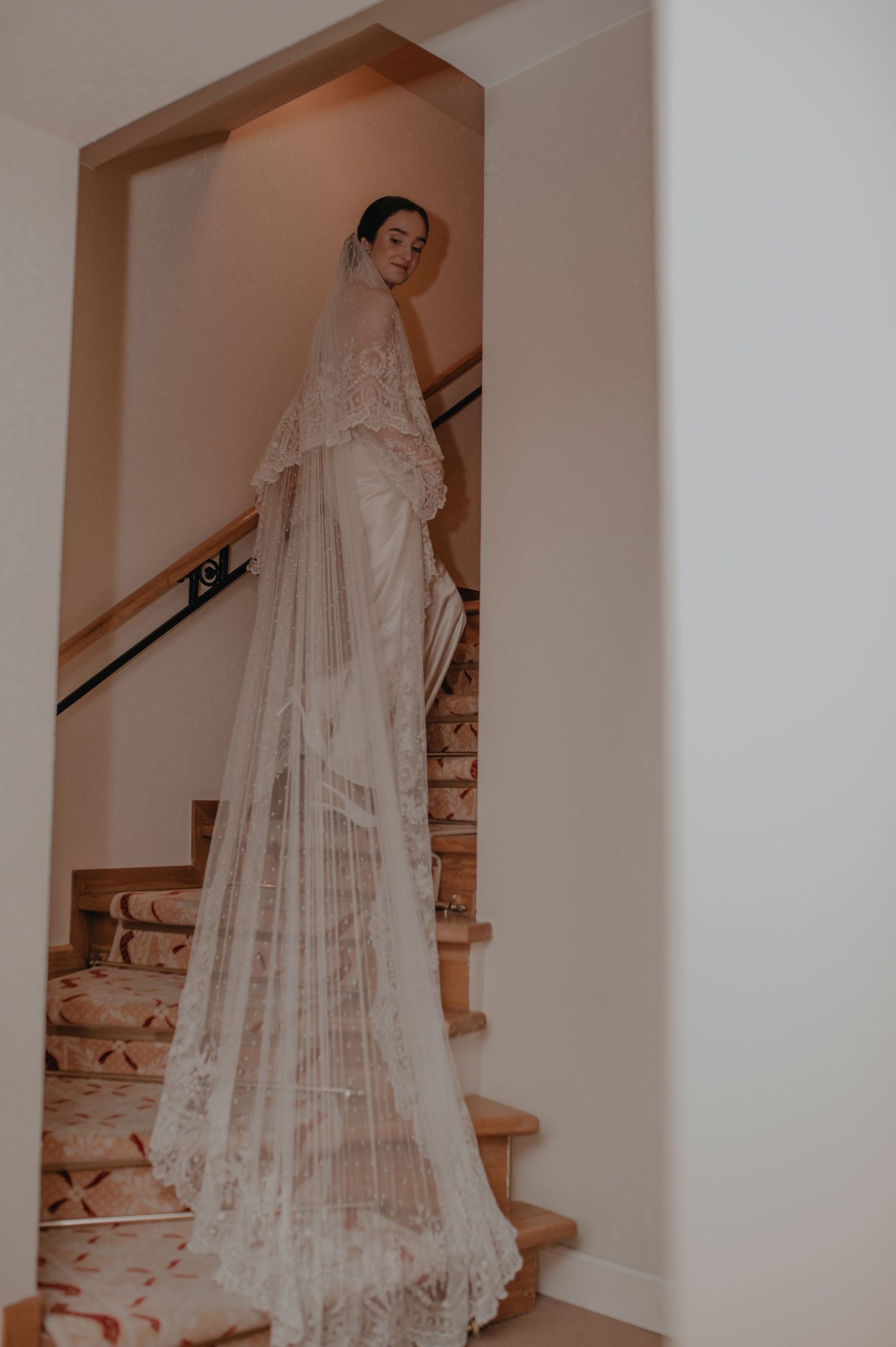 A bride in a flowing lace veil ascends a white staircase in a series of elegant wedding photos.