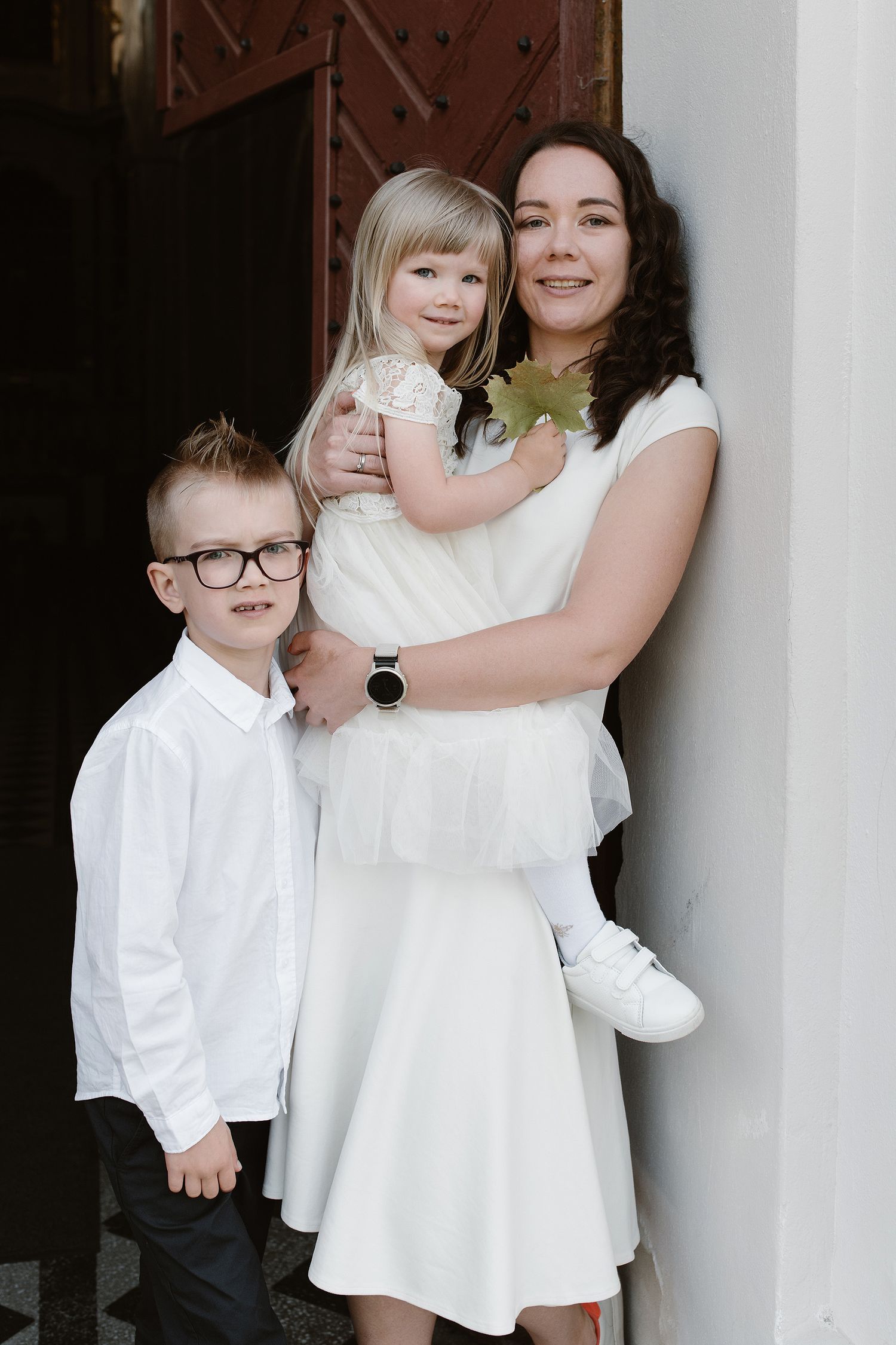 A series of black and white portraits showing tender moments between family members in coordinating white outfits.