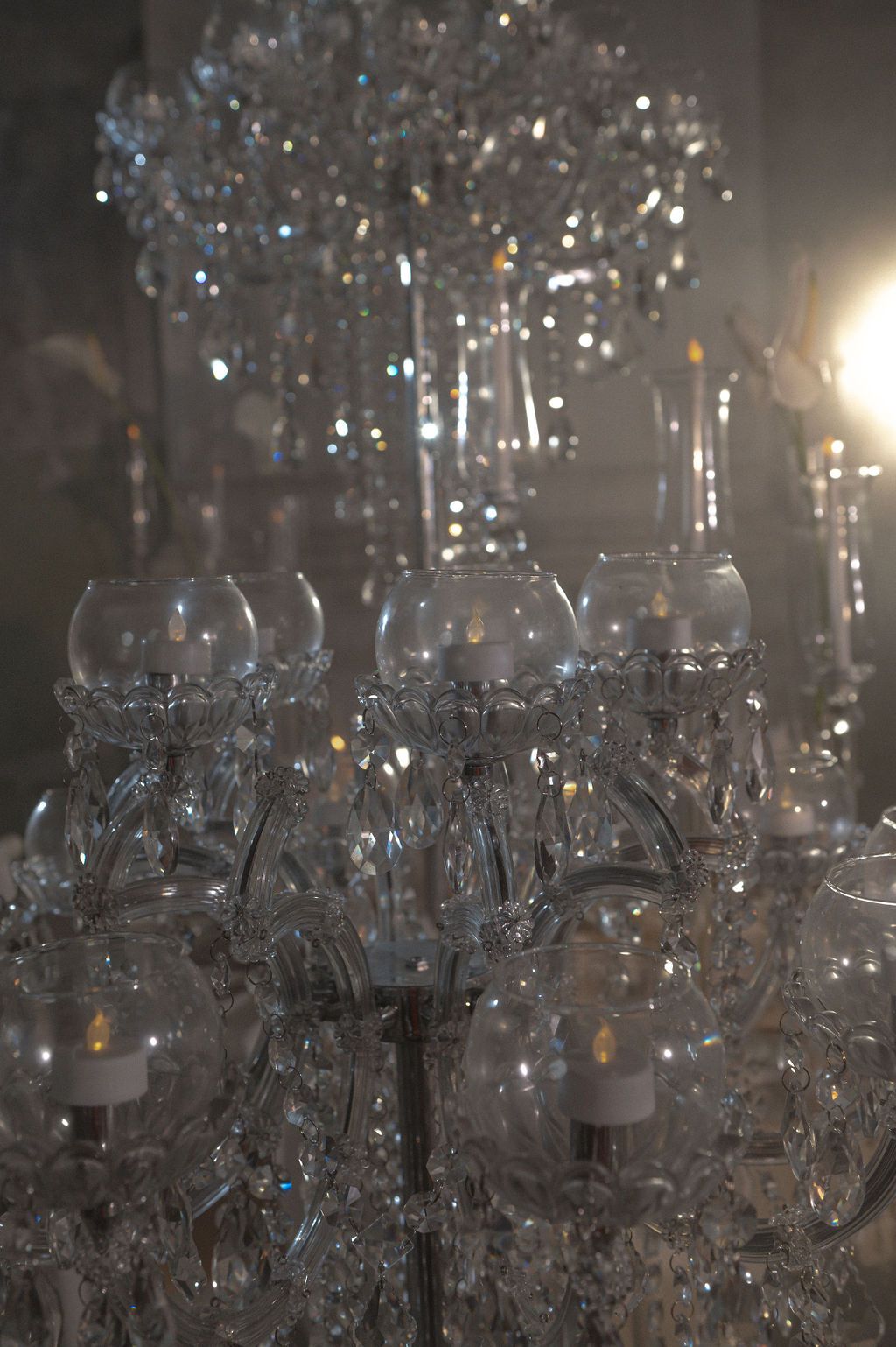Elegant crystal chandelier with glass candle holders and sparkling prisms glowing in a dimly lit room.