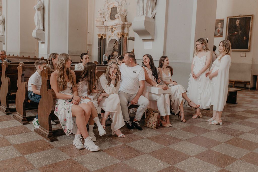 Group of people in white outfits seated in a church during a religious ceremony or celebration.