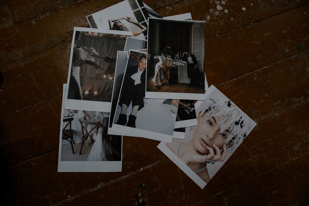 A collection of black and white polaroid photos scattered on a rustic wooden floor capturing elegant moments.