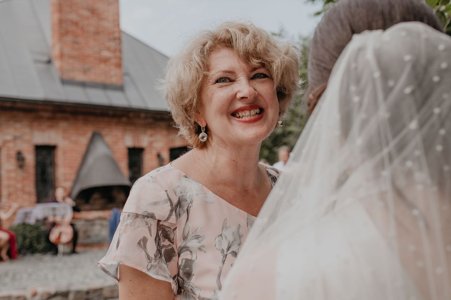 Candid outdoor moment at a wedding celebration with brick building in background.
