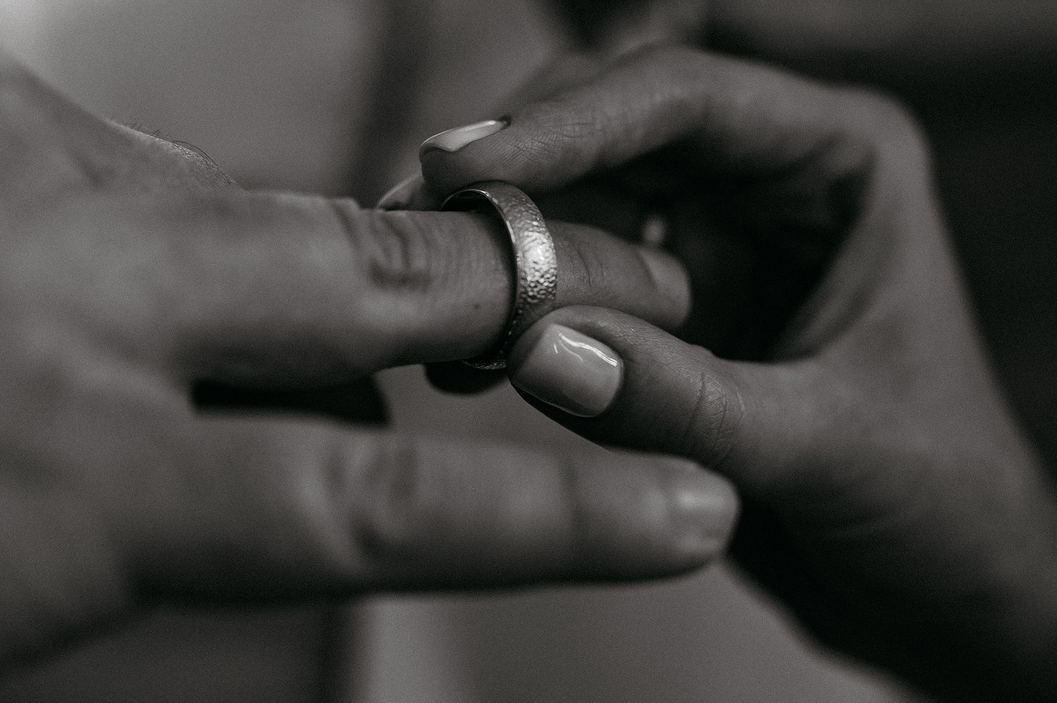 Black and white close-up photo of hands exchanging a small object between them.