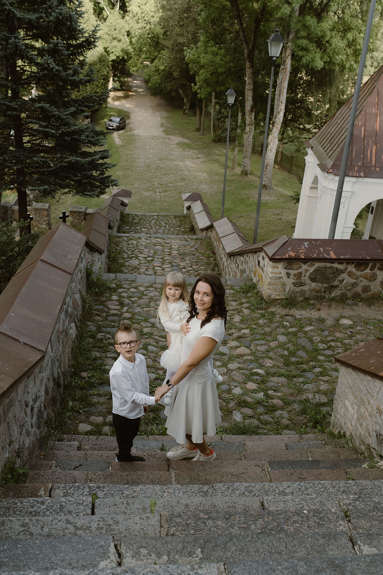 Three images of people walking down stone steps in a wooded outdoor setting surrounded by trees and stone walls.