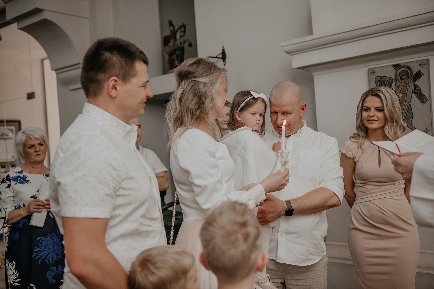 A small group of people gather together in white attire for an intimate indoor celebration.