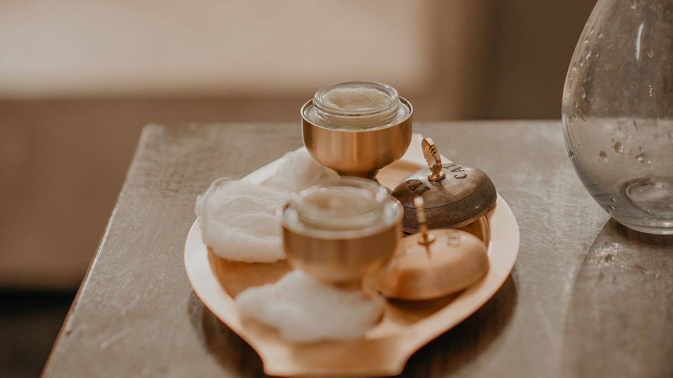 Small glass jars filled with honey or caramel desserts arranged on a white ceramic plate in warm lighting.
