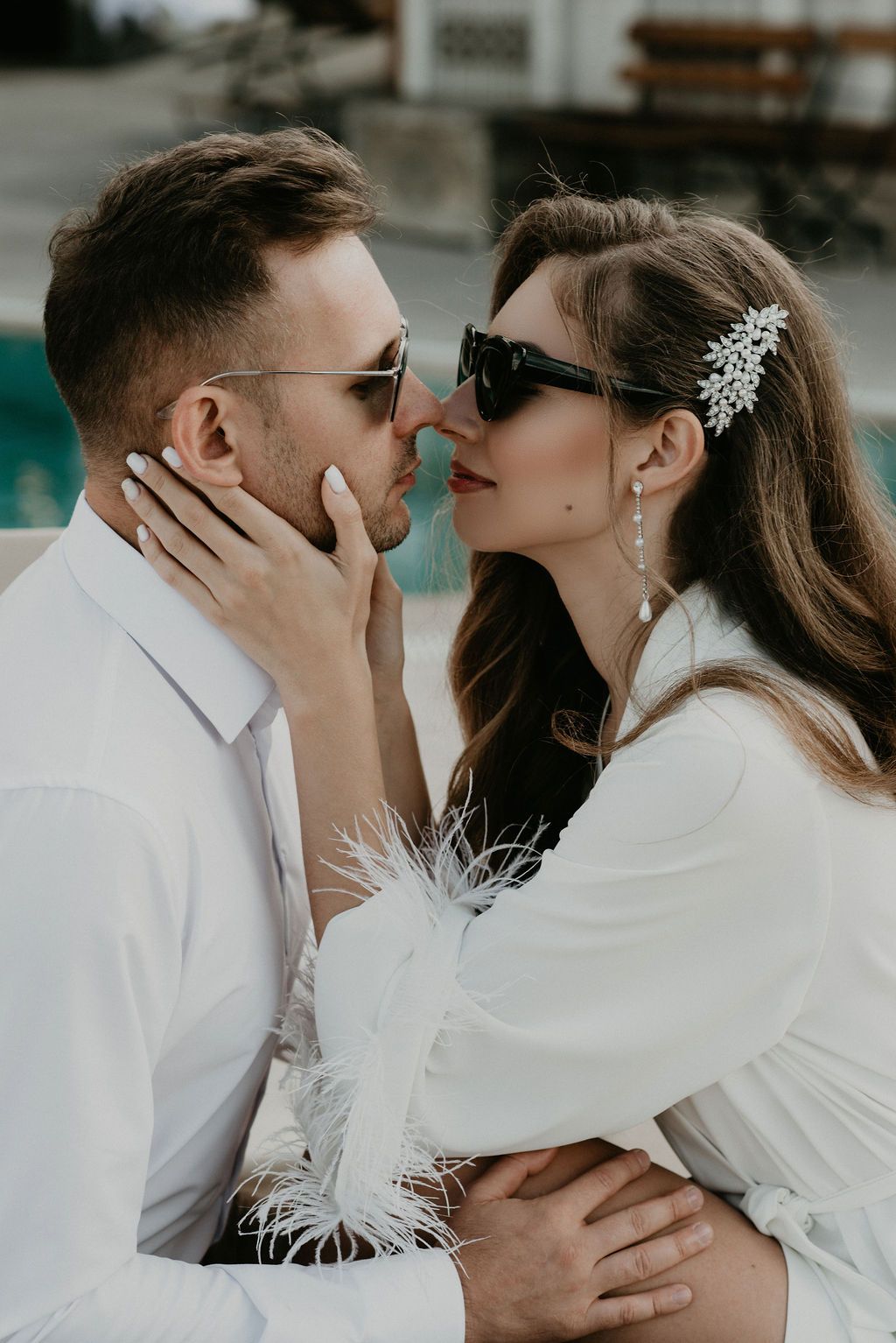 Stylish wedding couple in sunglasses sharing a romantic moment, bride in white feathered dress.