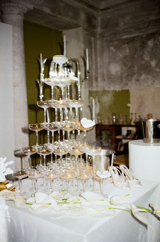 Elegant champagne tower with stacked glasses on a white tablecloth at a wedding reception.
