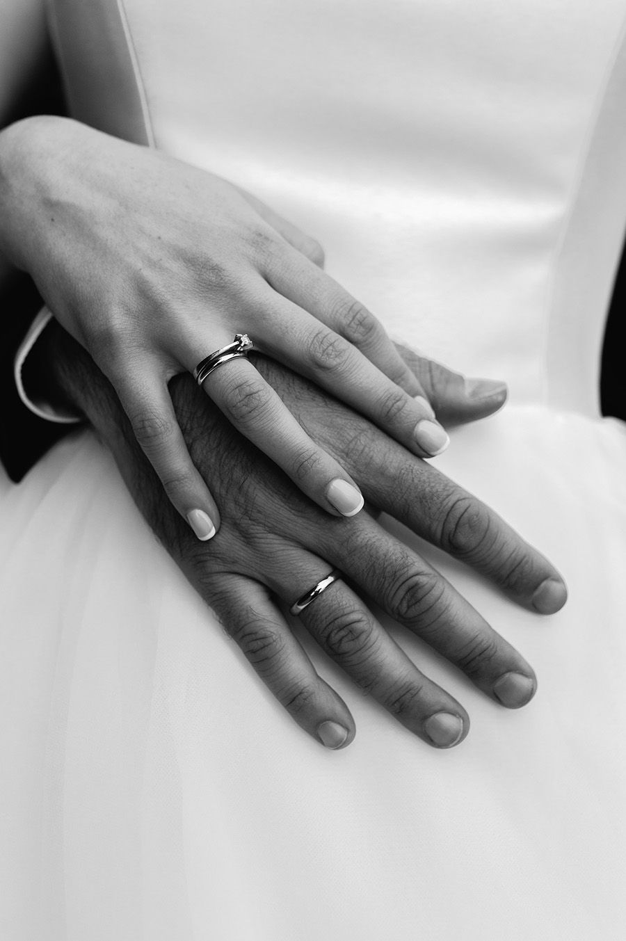 Black and white photo series showing two hands with wedding rings resting together on a white surface.