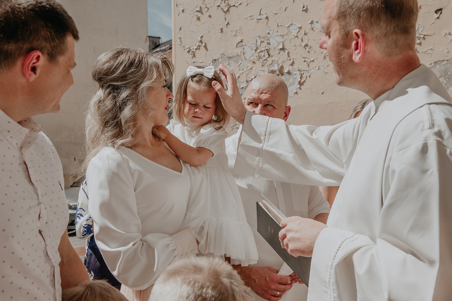Wedding party dressed in white laughs together during joyful candid moment at celebration.