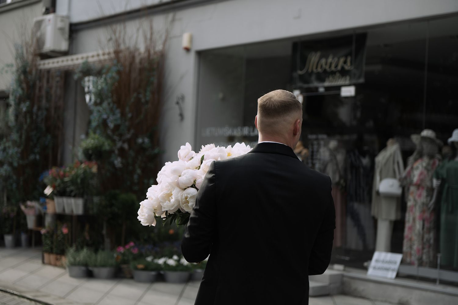 Elegant wedding photography session outside storefronts with soft floral decorations.