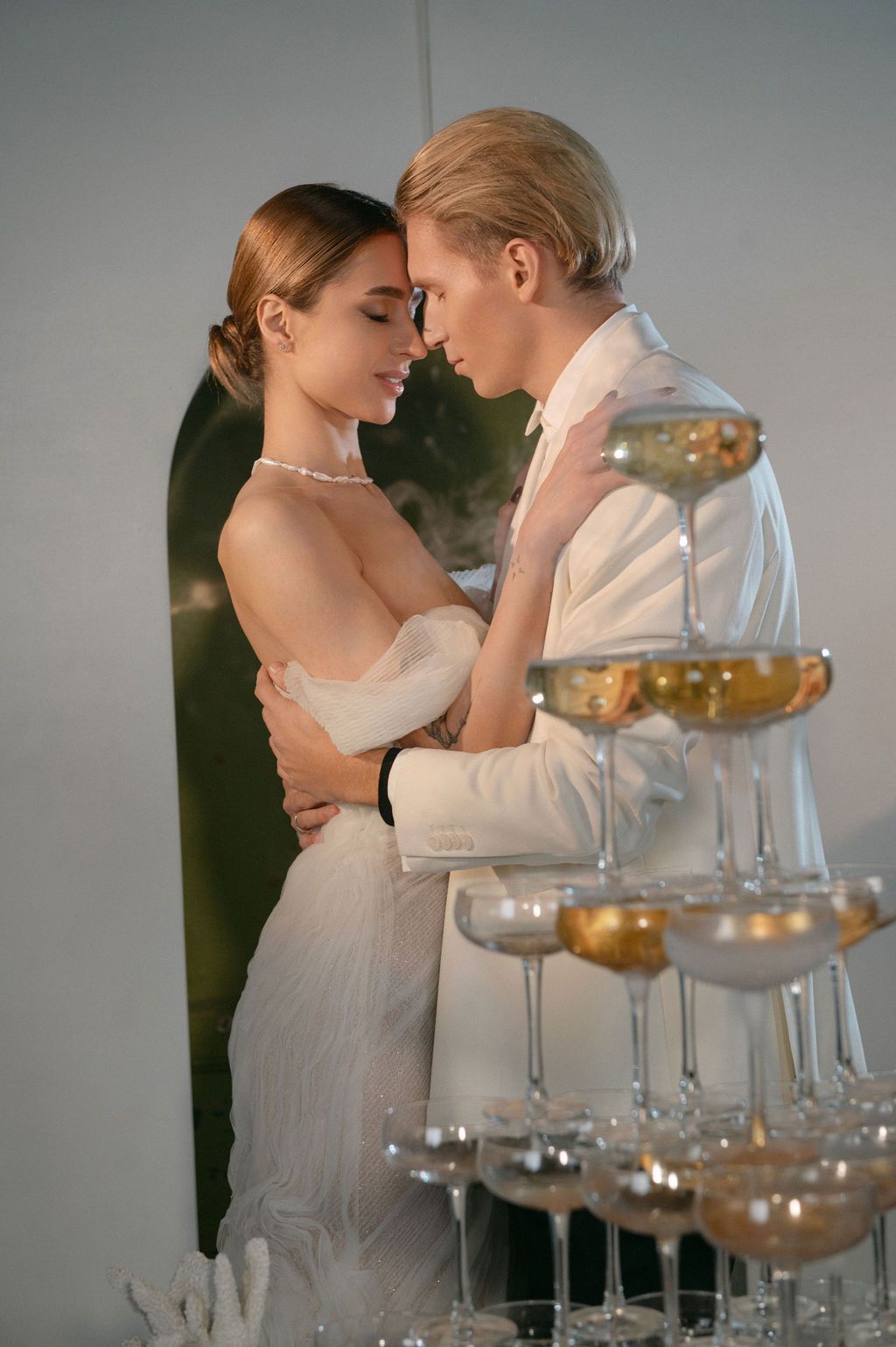 Romantic bride and groom embracing beside a champagne tower at their elegant wedding reception.