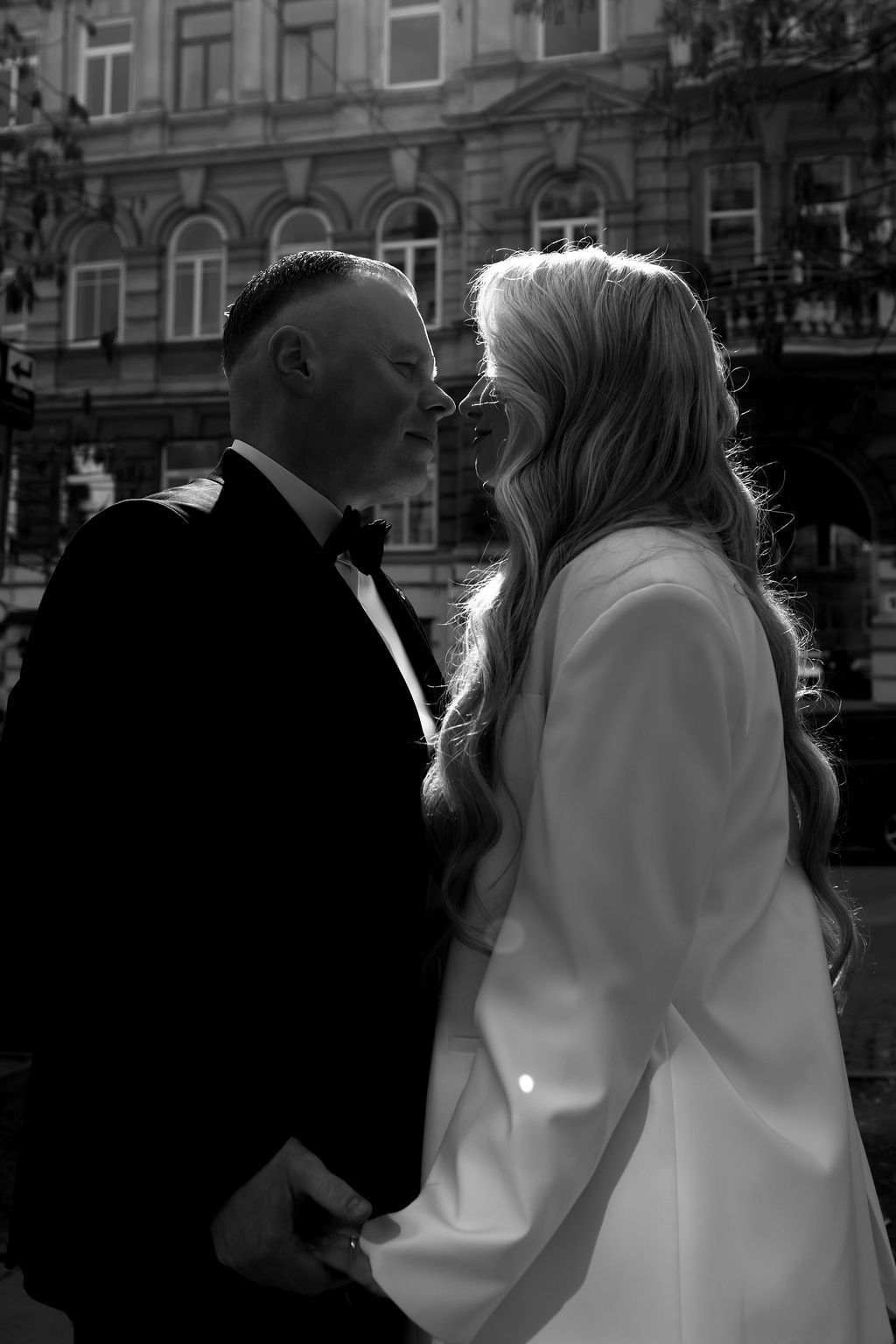 Black and white photo of a bride and groom sharing an intimate moment on a city street.