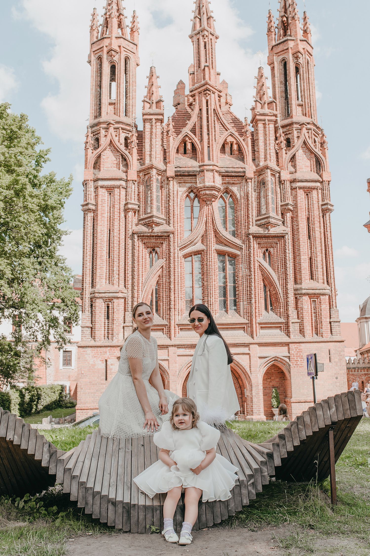 A series of photos showing people posing in front of a pink Gothic church with ornate spires and architectural details.