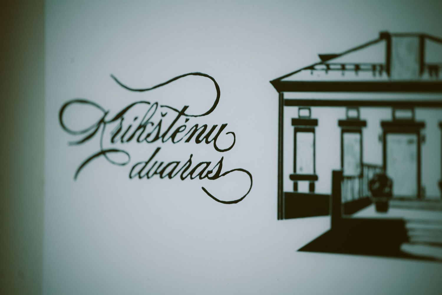 Elegant calligraphy logo of Krikstenu Dvaras with a classic manor house illustration in monochrome.