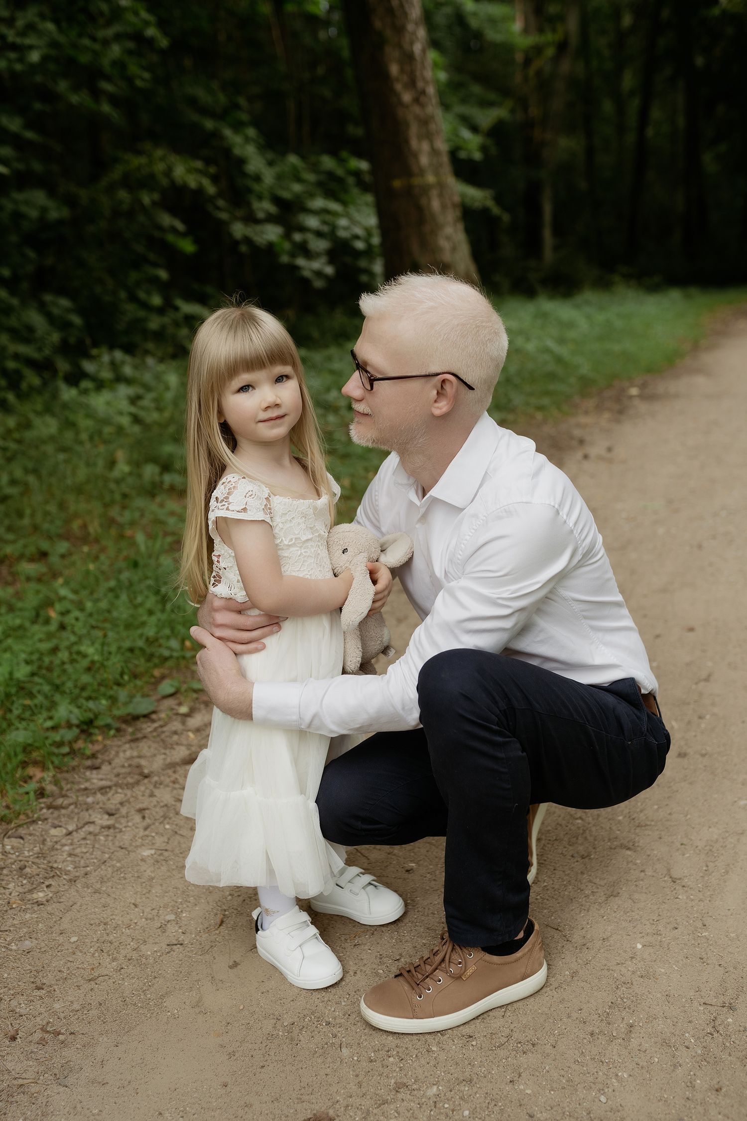 A tender moment shared between parent and child on a dirt path in a lush green forest setting.