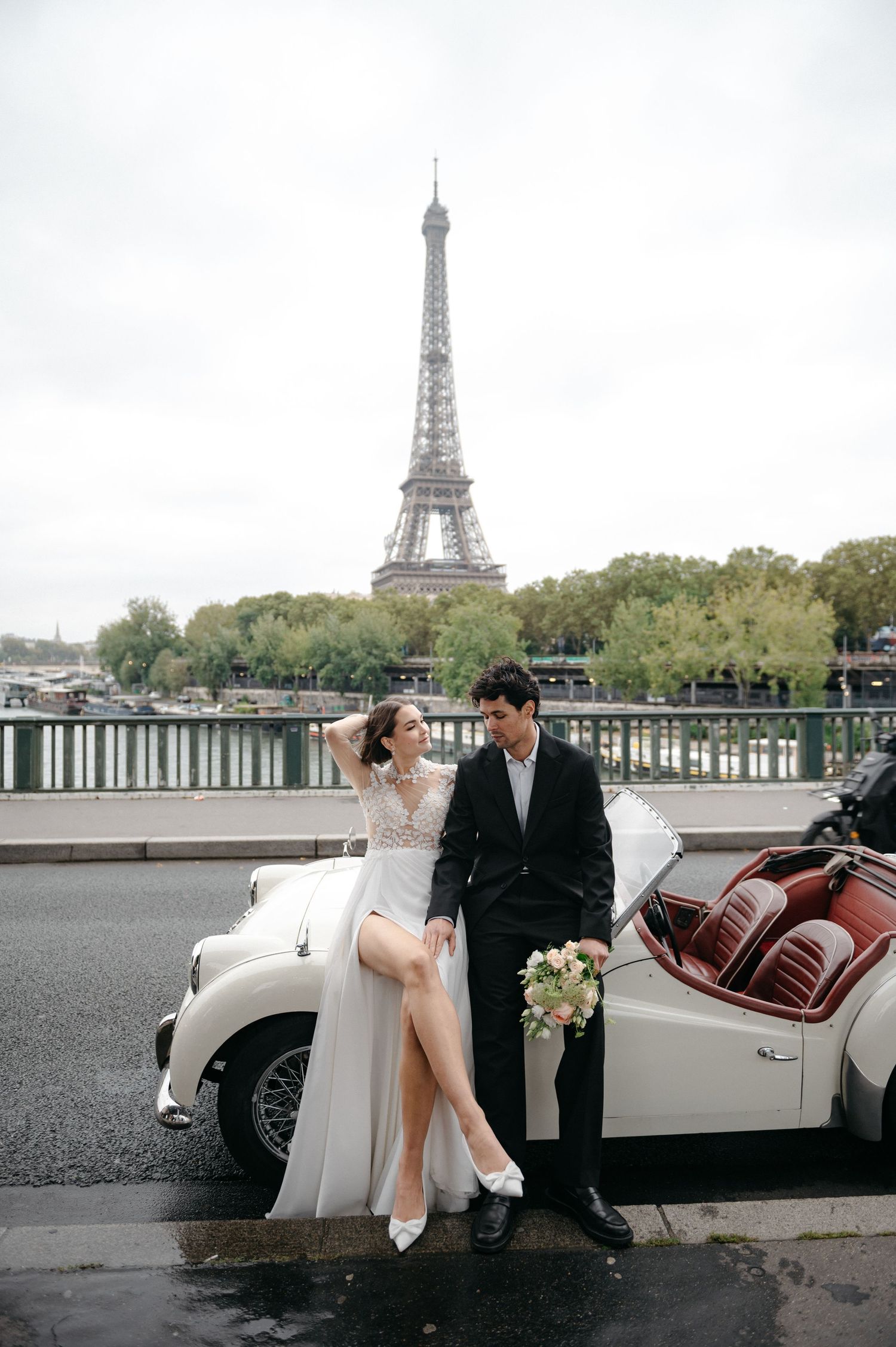 Romantic wedding photo shoot in Paris with vintage white car and Eiffel Tower in background.