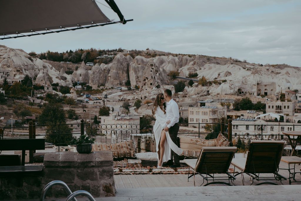 Romantic couple embracing on a rooftop terrace overlooking the iconic fairy chimneys of Cappadocia, Turkey.