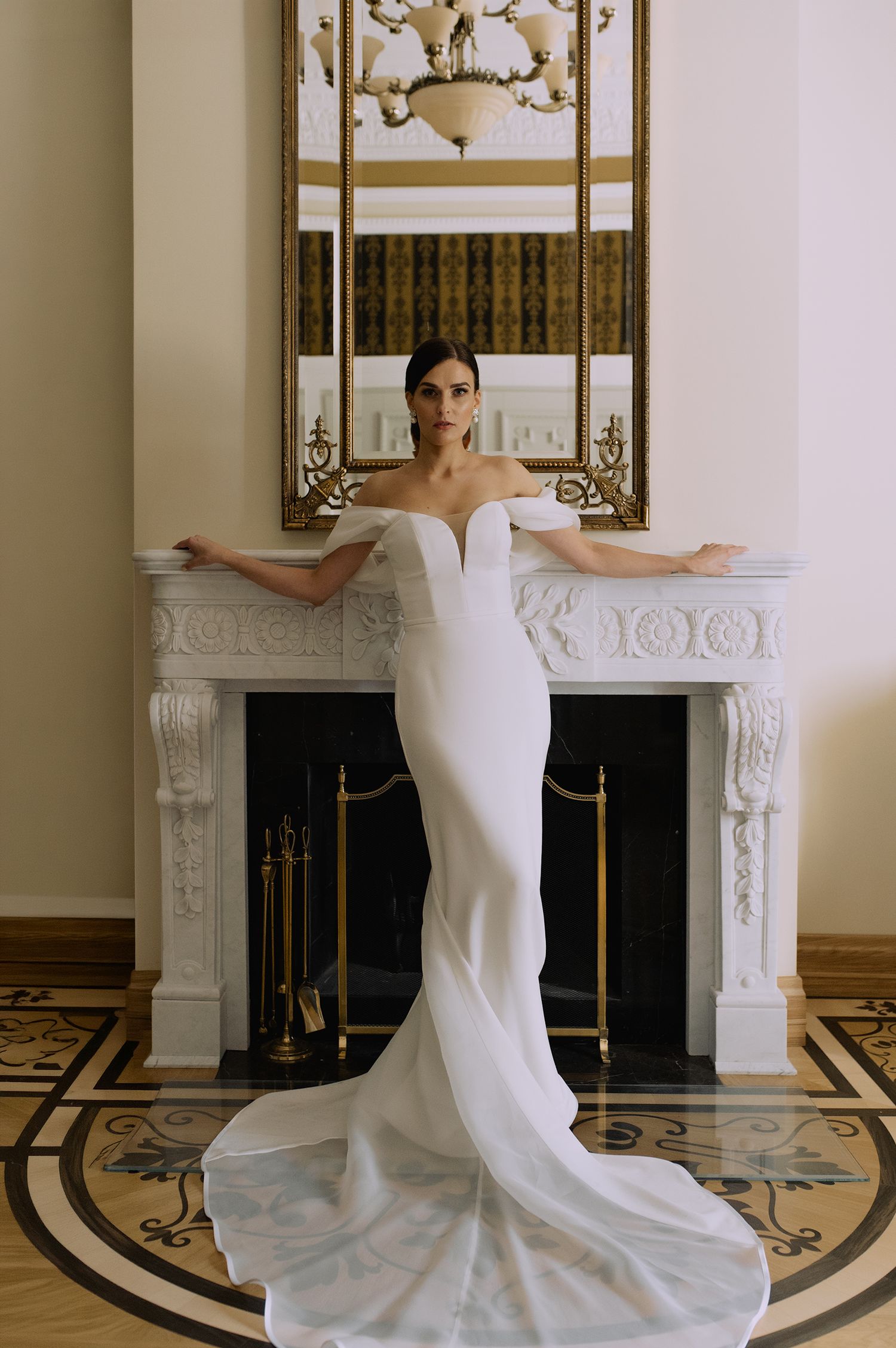 Elegant white wedding dress with dramatic train photographed in sequence against ornate marble fireplace.
