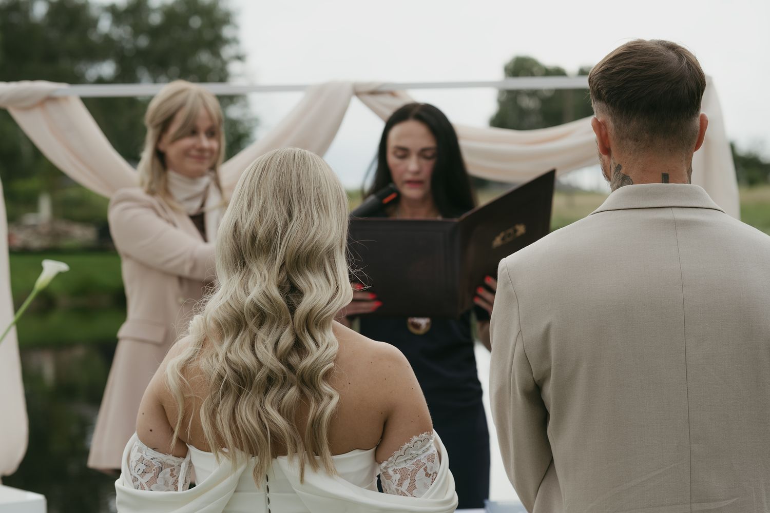 Wedding party celebrates under a white tent during an outdoor reception at dusk.