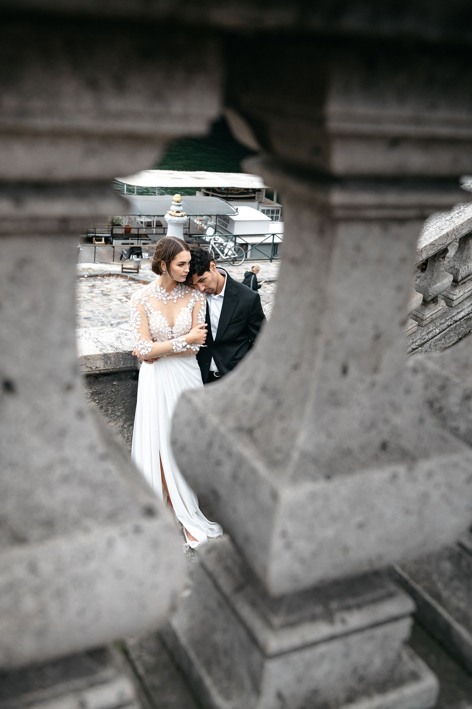 A romantic couple embraces on stone steps in black and white with selective focus and dramatic lighting.