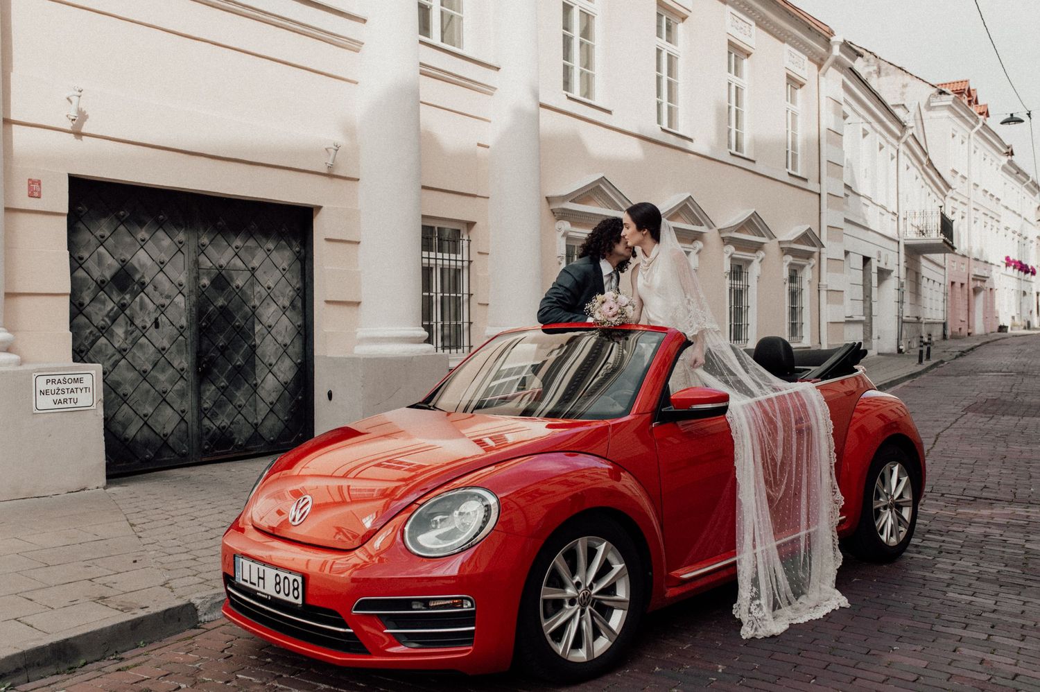 Red luxury sports cars parked along a white building facade on a cobblestone street.