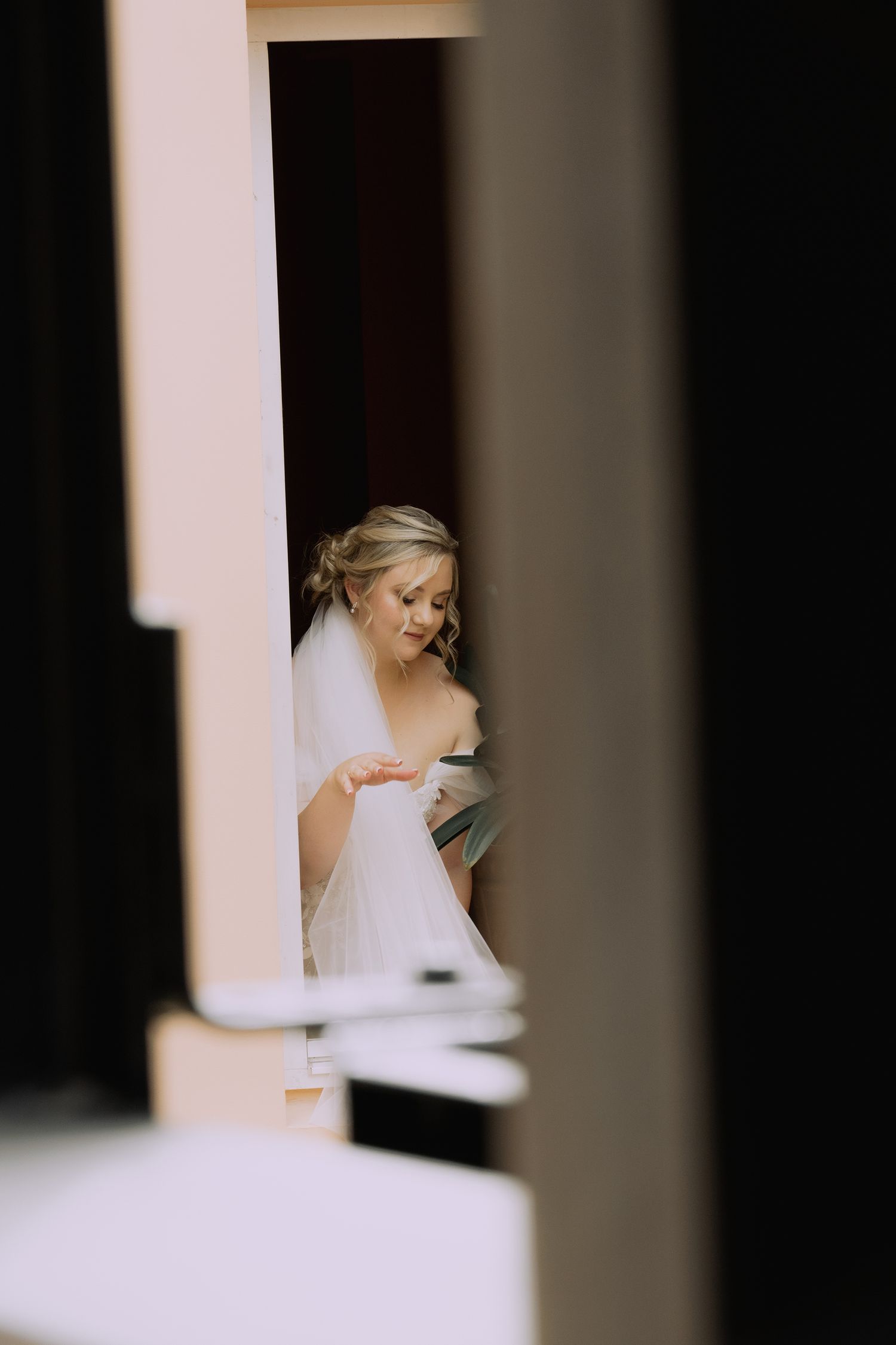 A bride in a white veil is captured in an artistic, minimalist composition with strong architectural framing.