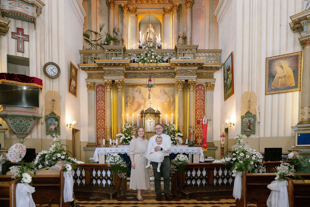 Couple posing at ornate church altar decorated with white flowers during a wedding ceremony.