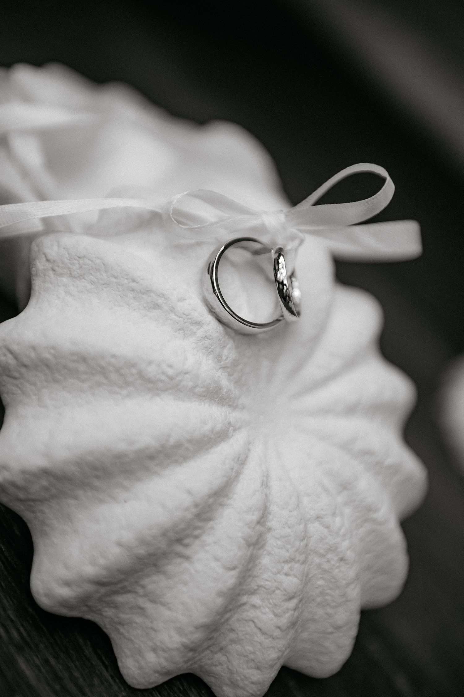 Black and white close-up images of wedding rings resting on delicate white fabric in artistic composition.