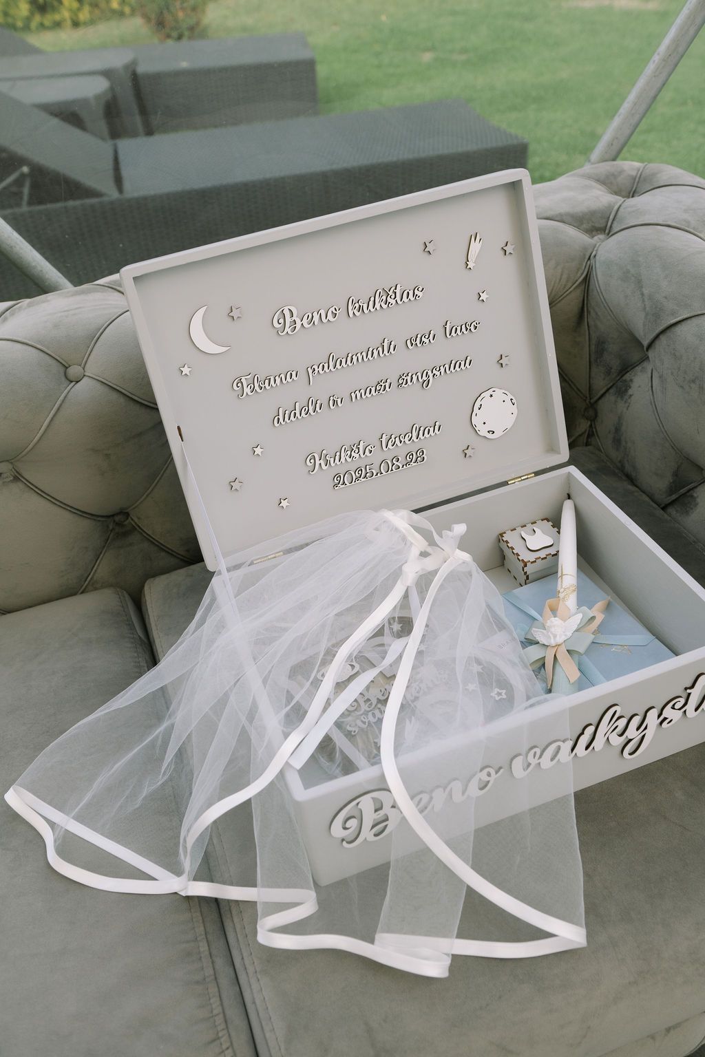 Elegant white wedding keepsake box with tulle, ribbon, and engraved text displayed open on a gray sofa.