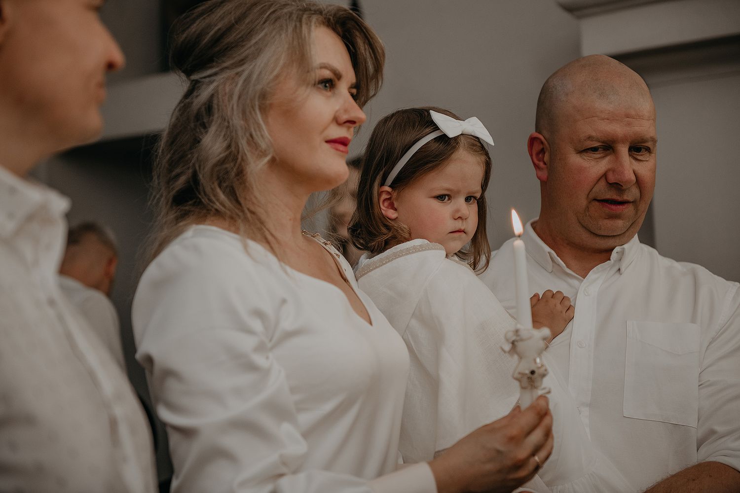 Group gathering in white attire sharing emotional moments together at an indoor event.