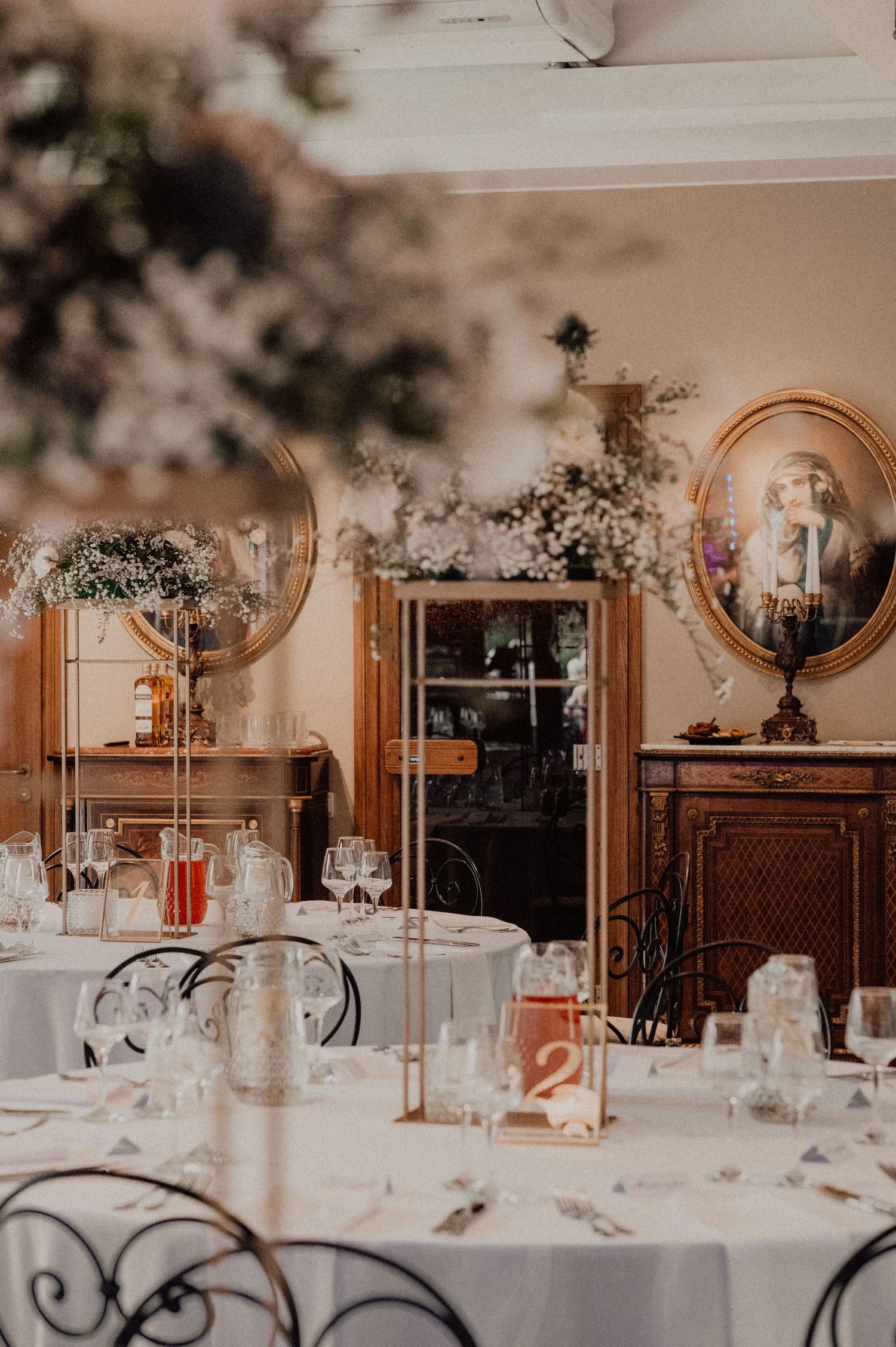 Wedding reception tables decorated with crystal glassware and floral centerpieces in an ornate ballroom setting.