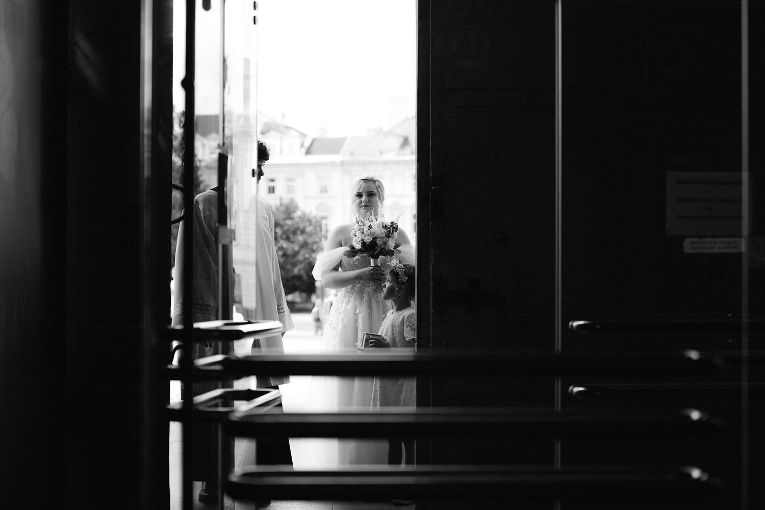A dark silhouette of a person stands in a dimly lit interior space with dramatic window lighting.