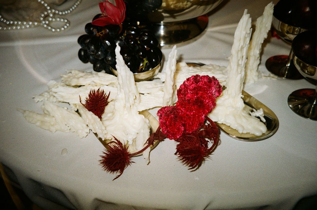 Elegant white swan sculptures made from cream with red carnations and dark grapes on a decorative table display.