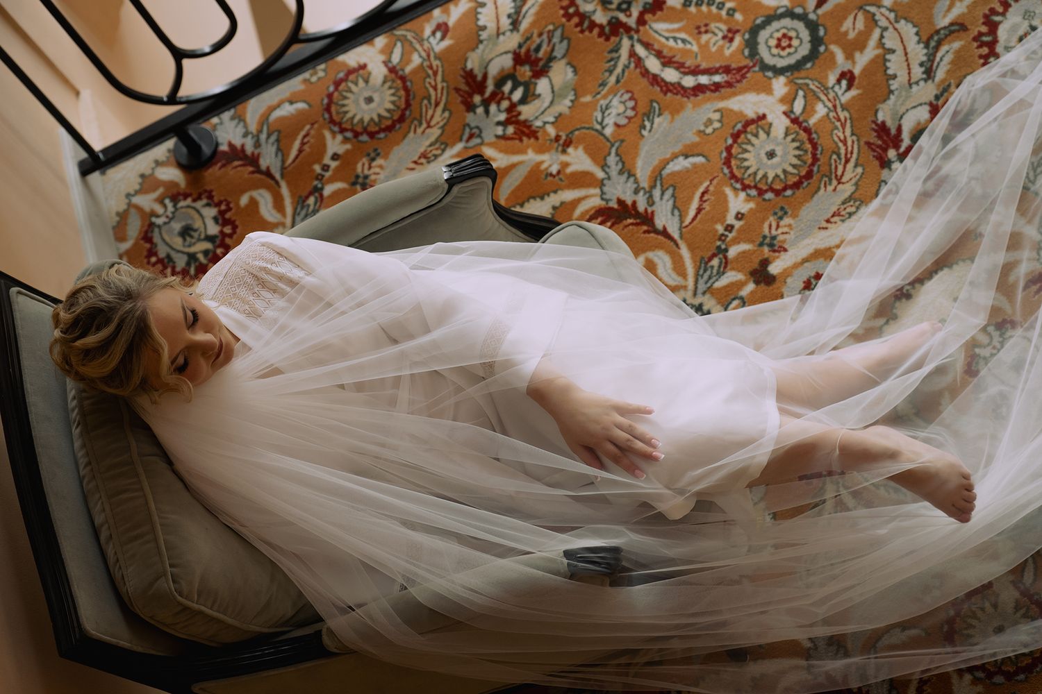 A flowing white wedding dress train trails elegantly across a decorative patterned floor.