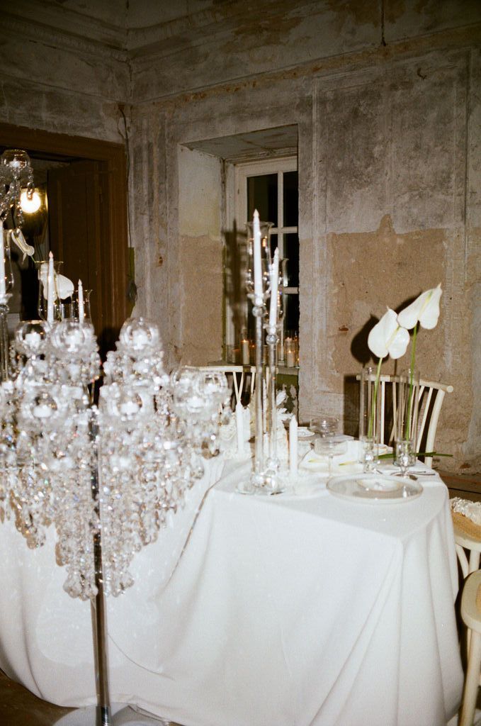 Elegant wedding reception table with crystal candelabras, white linens, and floral centerpieces in a rustic venue.