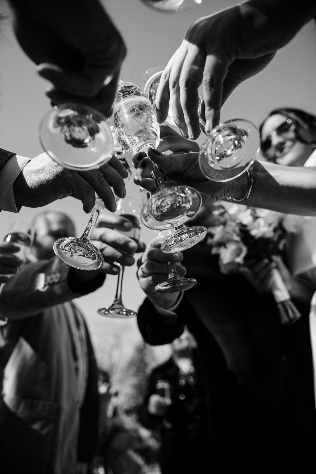 Black and white photo of people clinking champagne glasses together in a celebratory toast at a formal event.