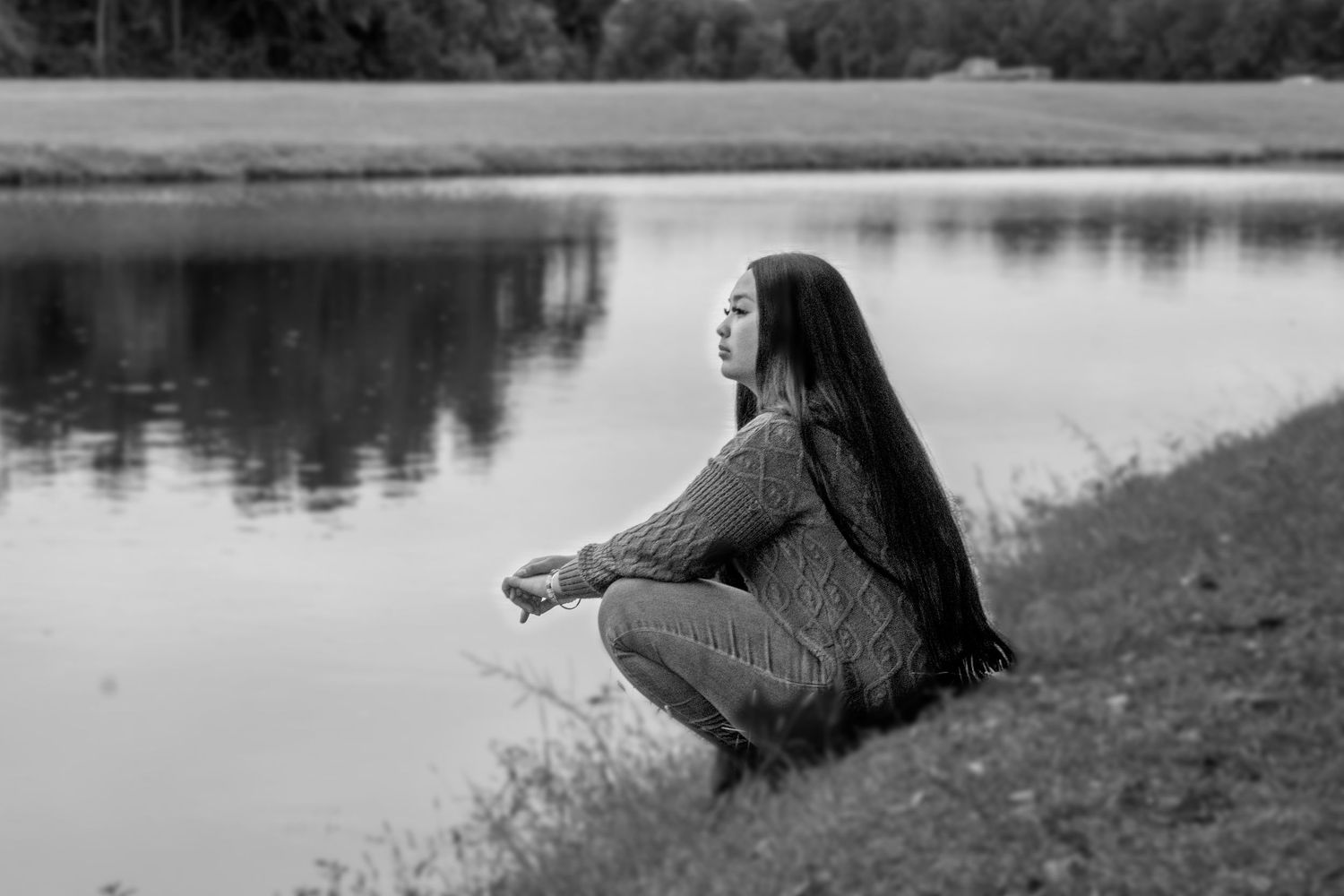 Silhouetted figure sitting by tranquil lake during sunset photography session.