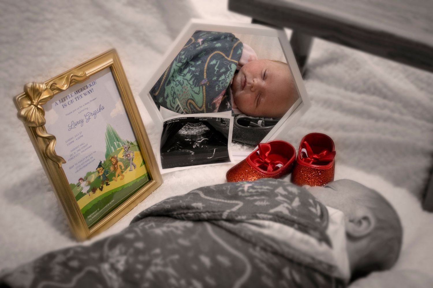 Still life arrangement of baby items and decorative frames on a gray surface.