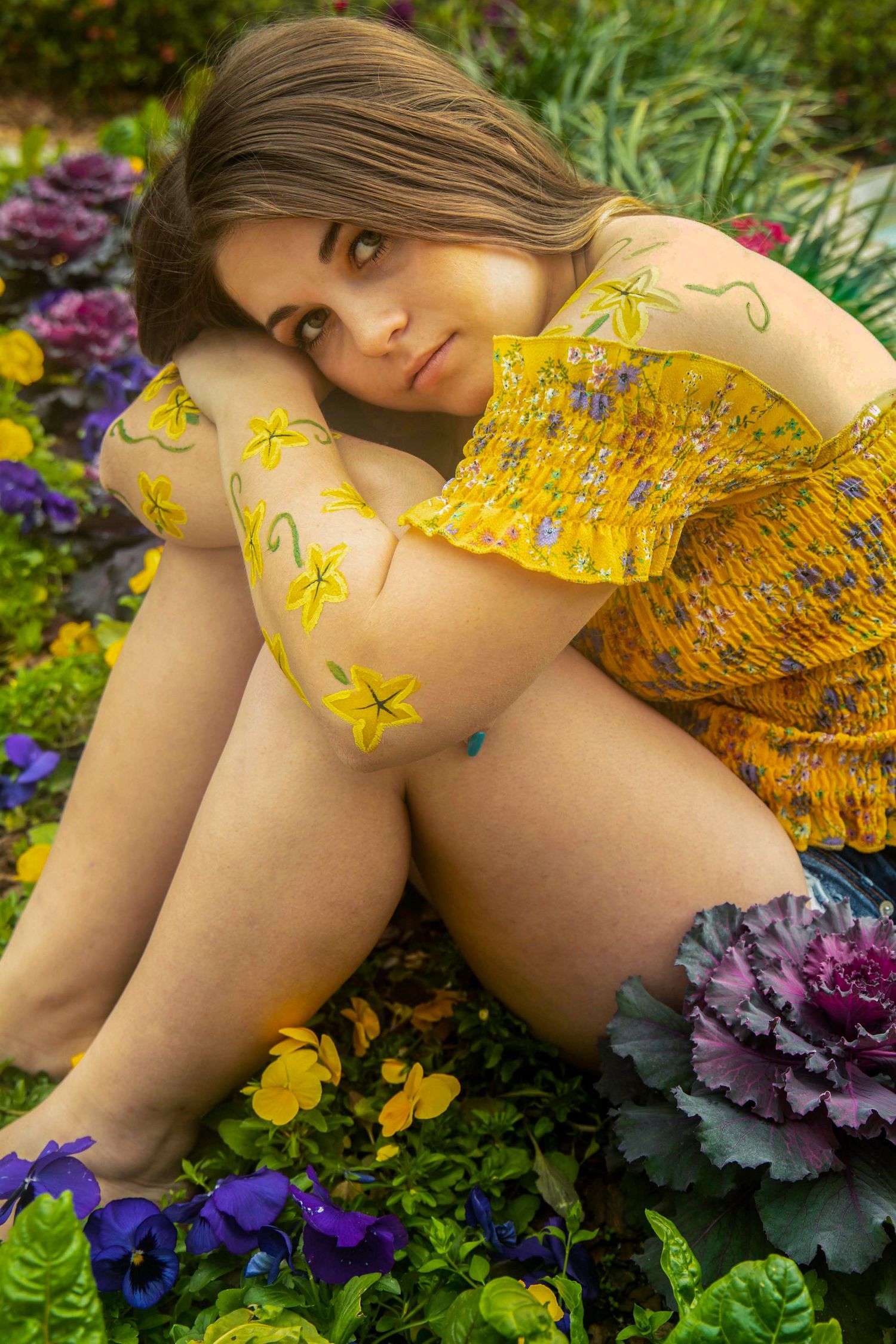 Yellow floral dress detail among purple ornamental cabbage and garden flowers.