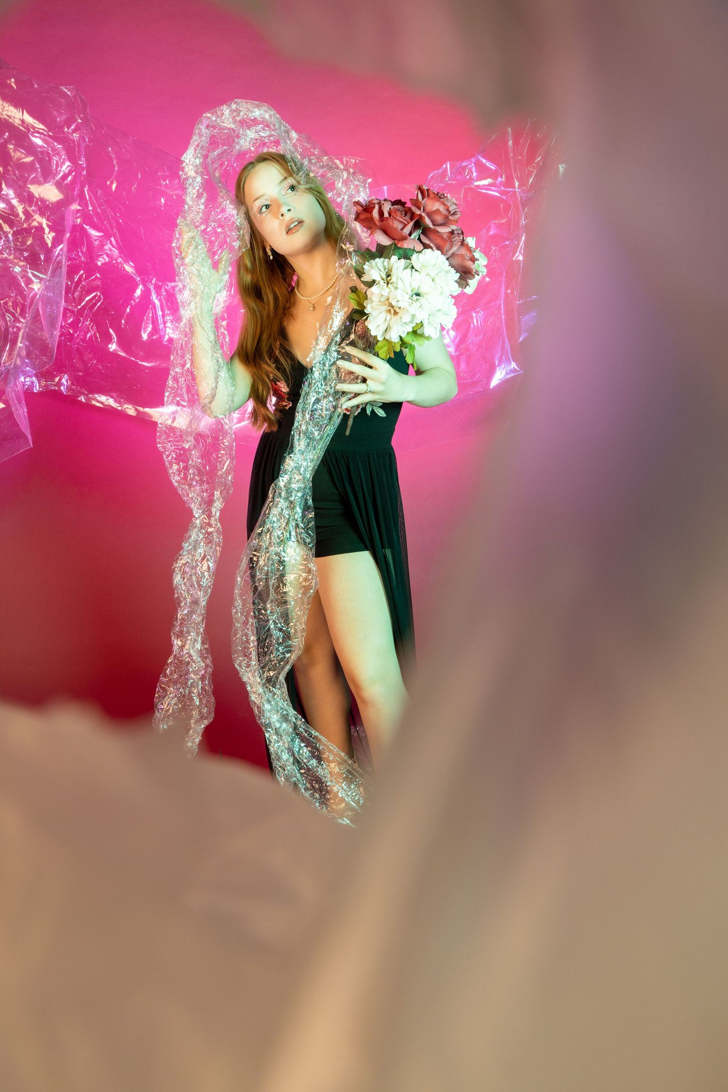 Ethereal fashion photo with roses and sheer fabric against pink background.