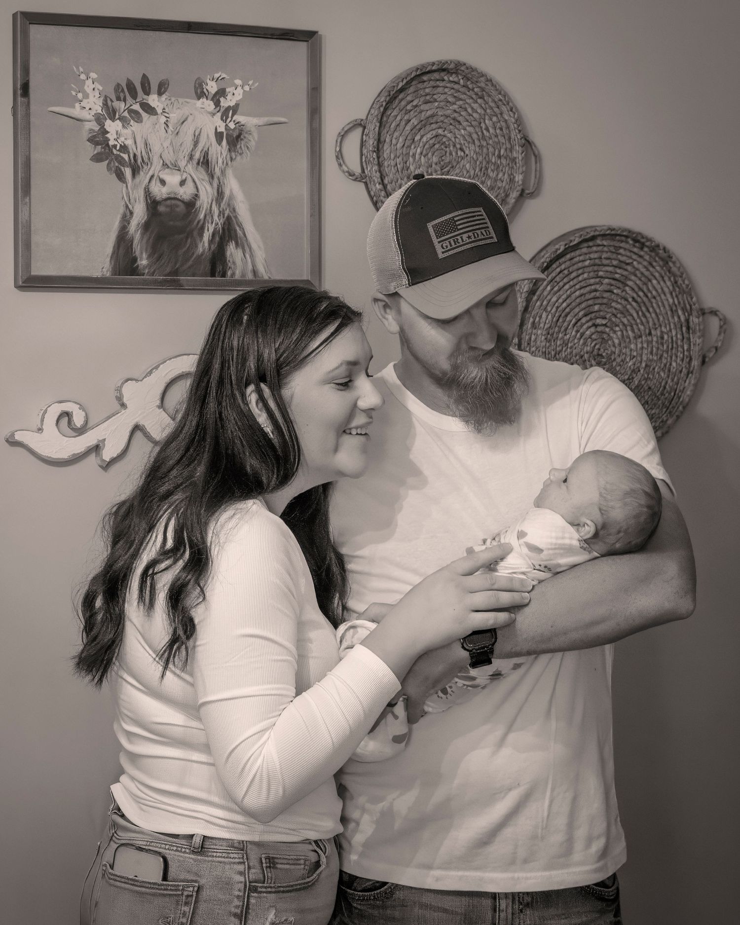 Family portrait with cow artwork in background and woven baskets on wall.
