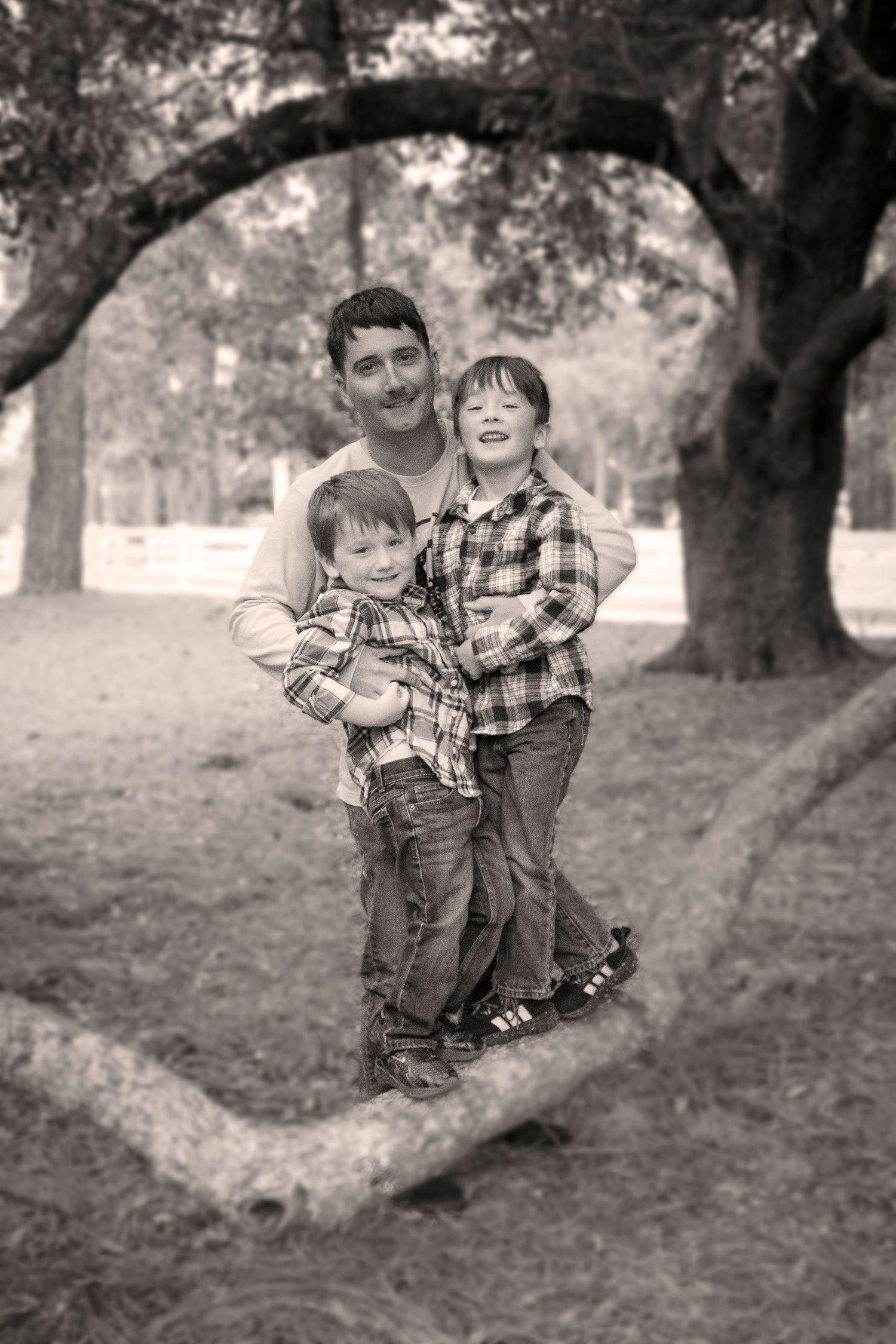 Black and white photo sequence of playful moments under a large tree in a park setting.