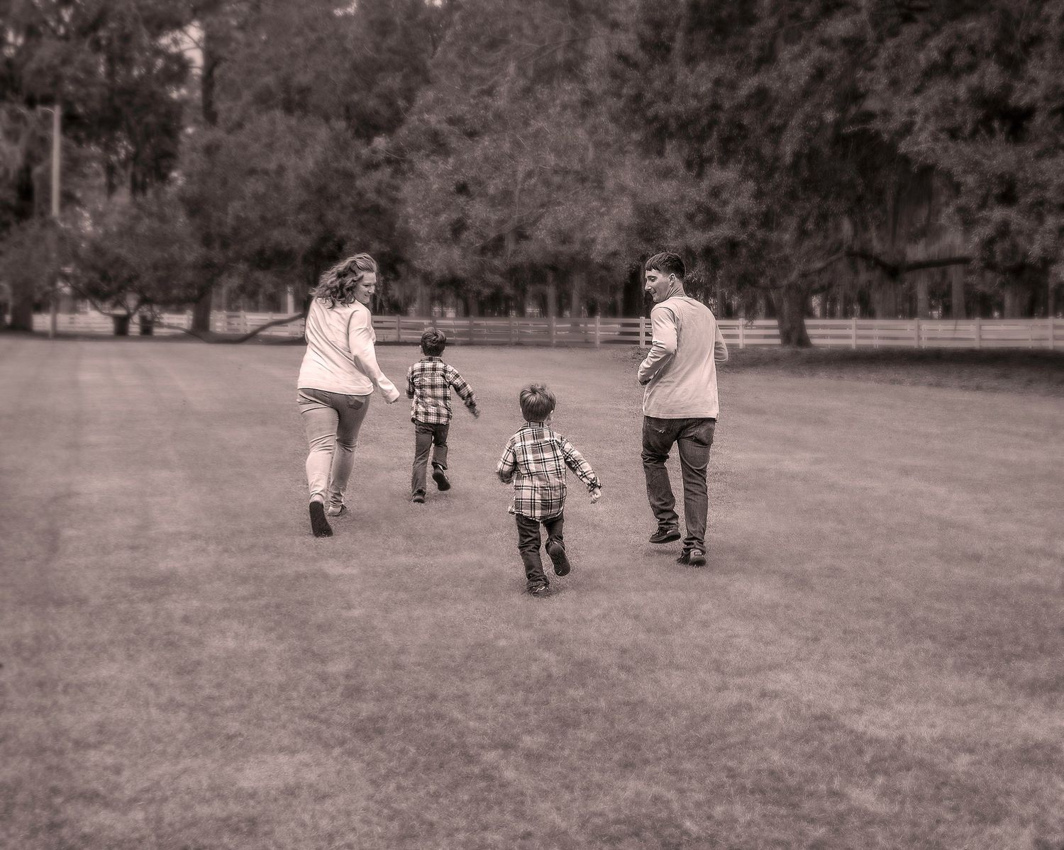 Children playing together in a grassy field captured in black and white.