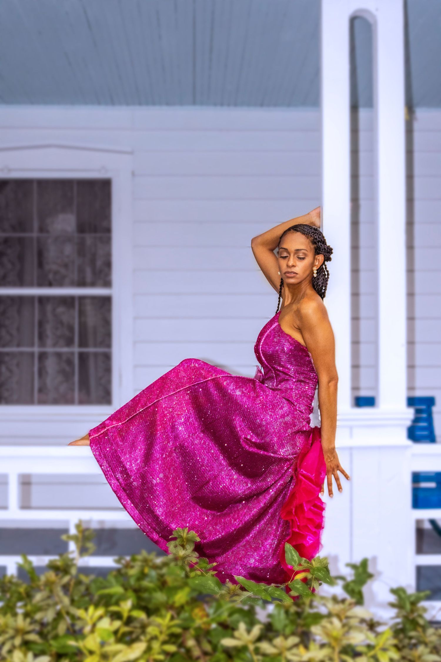 Dancer in flowing magenta dress performing against white house backdrop.