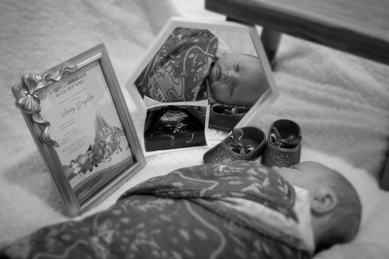 Artistic arrangement of baby items and frames in muted tones on textured surface.