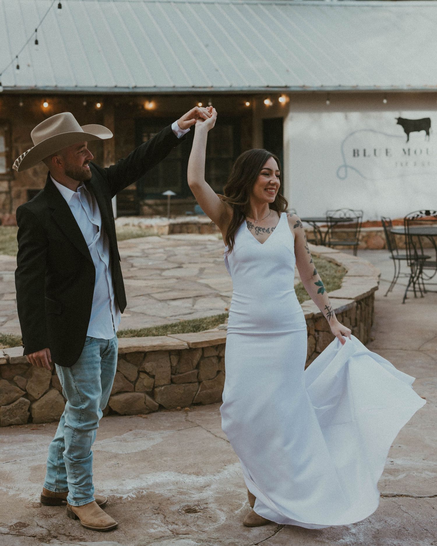 Wedding couple dancing outdoors on stone patio in natural lighting.