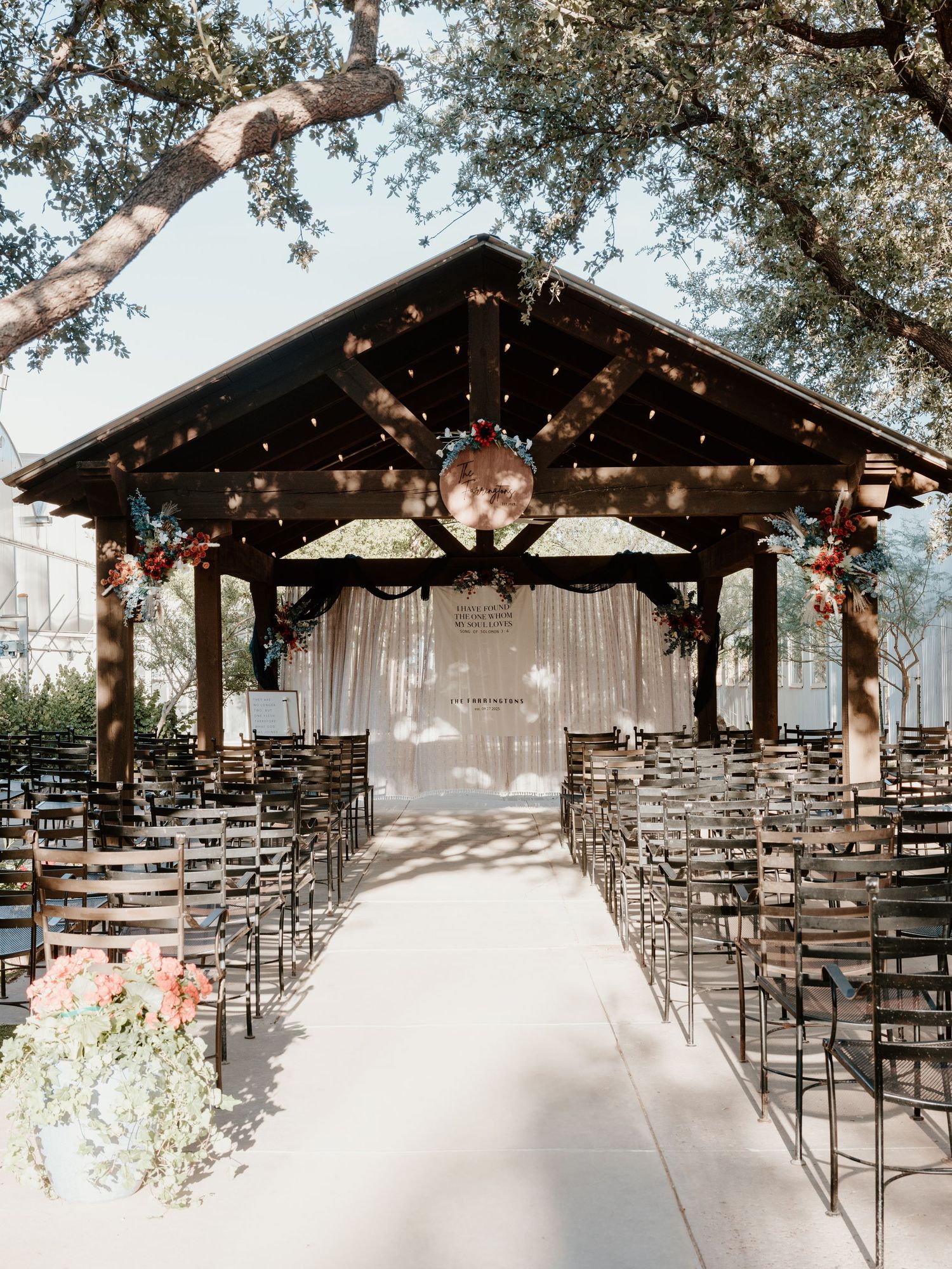 An outdoor wedding venue with string lights and rows of chairs under a rustic wooden pavilion.