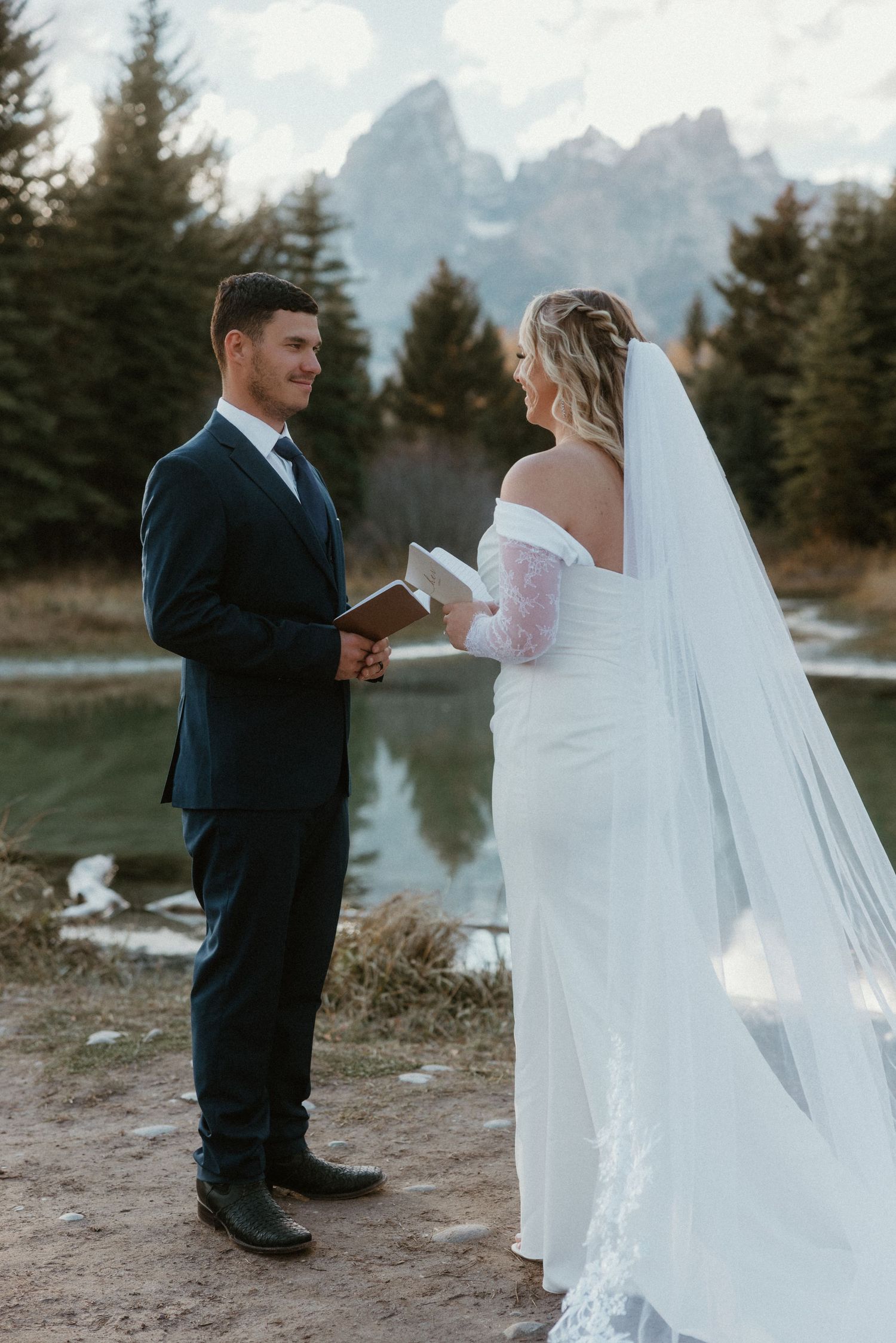 Wedding ceremony moment with couple exchanging vows against mountain backdrop.