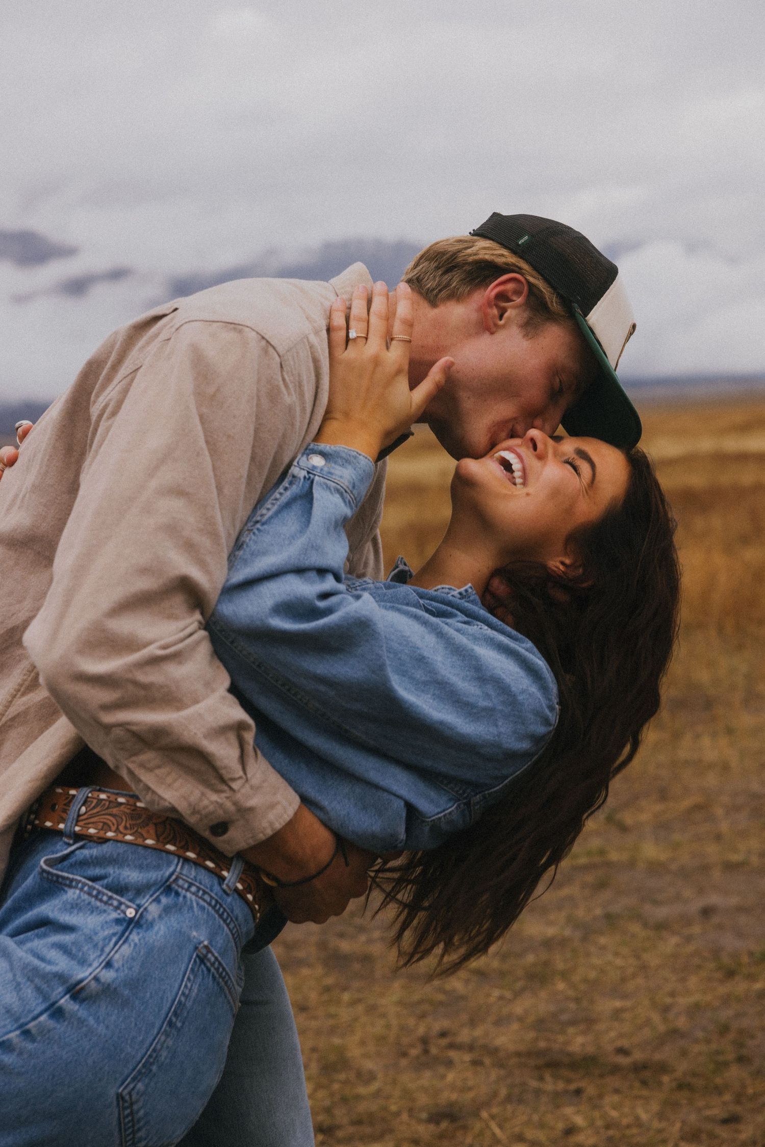 A romantic dance dip performed in a golden field with mountains in the background.
